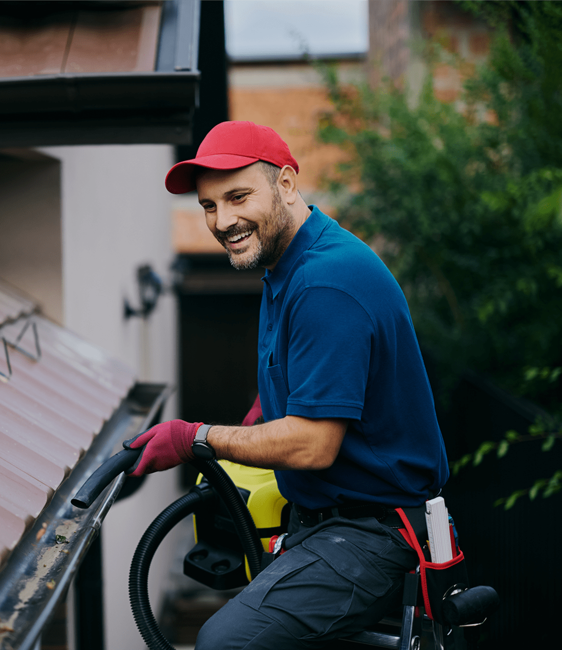 Man in red cap cleaning roof gutters