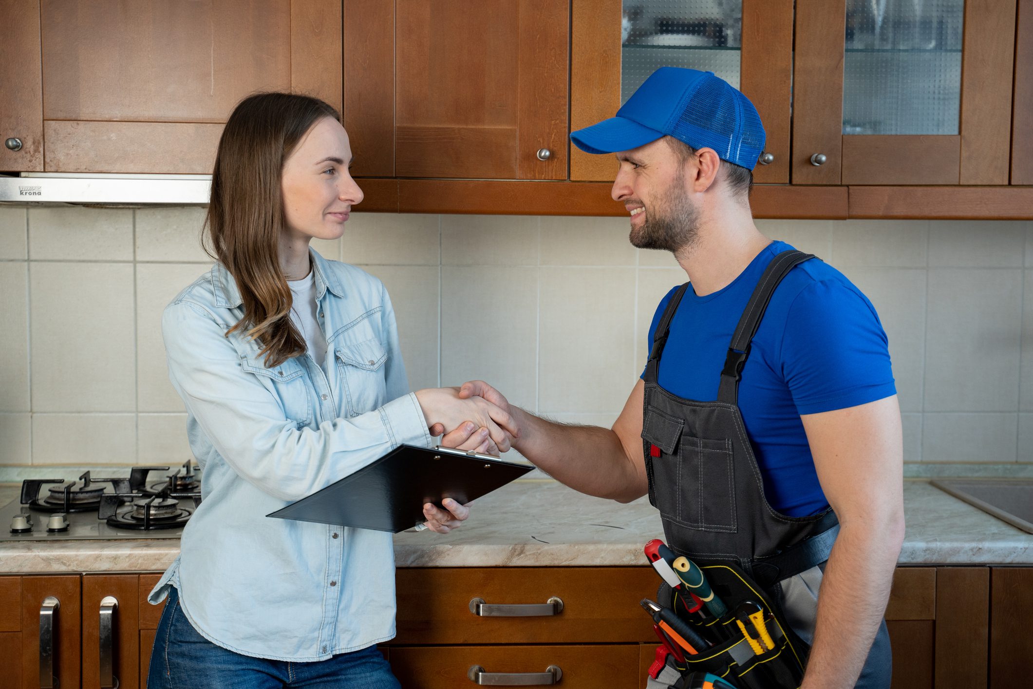 Woman shaking hands with a handyman in a kitchen.